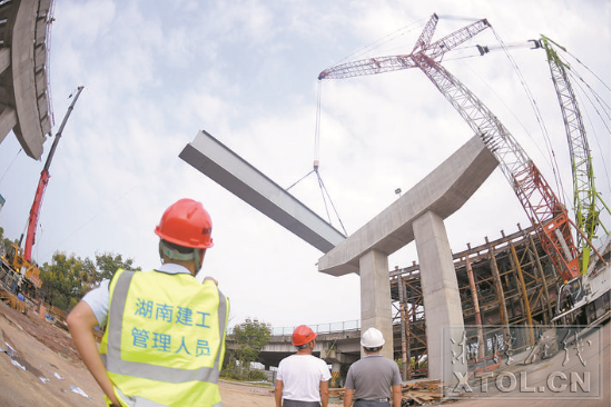 紅易-滬昆跨線橋跨滬昆高速公路主跨架梁施工現(xiàn)場，一節(jié)節(jié)鋼箱梁被吊起安裝。（記者 方陽 攝）